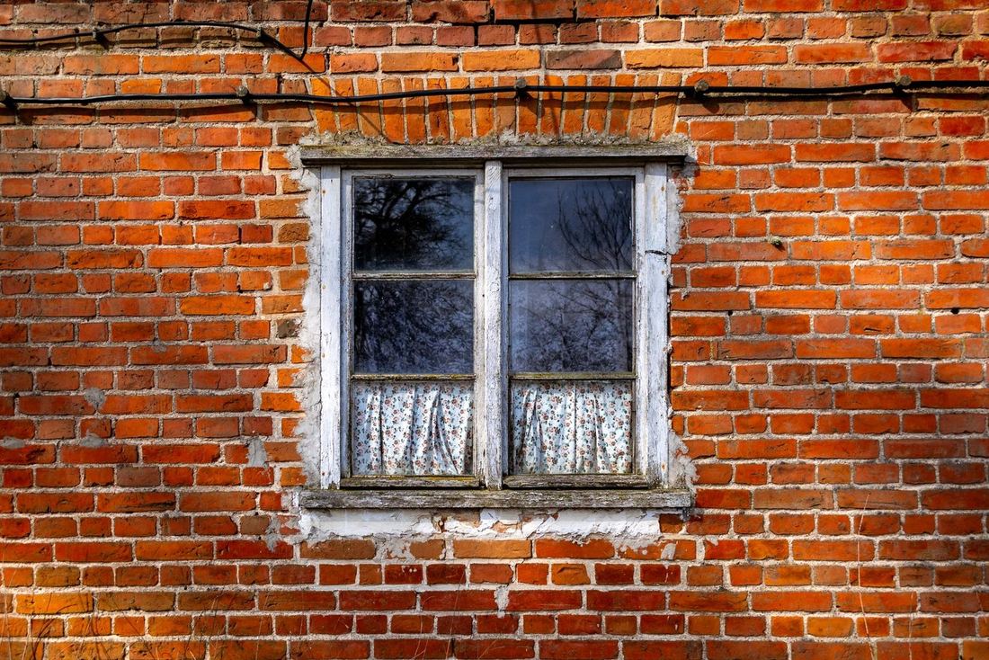 Stare drewniane okno skrzynkowe w ceglanym domu jesienią
